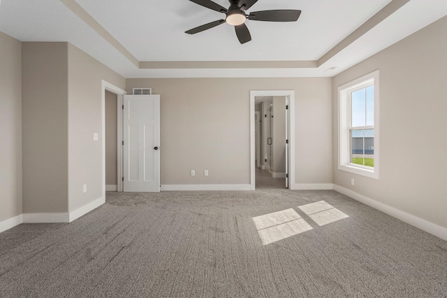 unfurnished bedroom with a raised ceiling, baseboards, carpet flooring, and visible vents