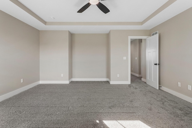 carpeted spare room featuring a raised ceiling, baseboards, a ceiling fan, and visible vents