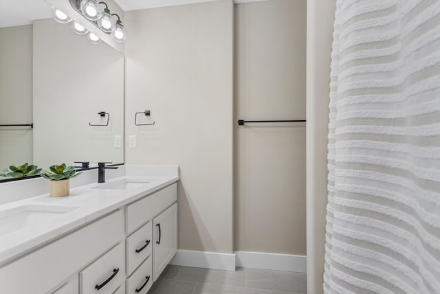 bathroom featuring double vanity, baseboards, a sink, and tile patterned flooring