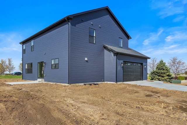 view of side of property with concrete driveway and a garage