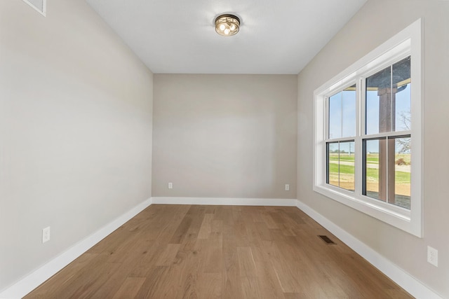 empty room with visible vents, baseboards, and wood finished floors