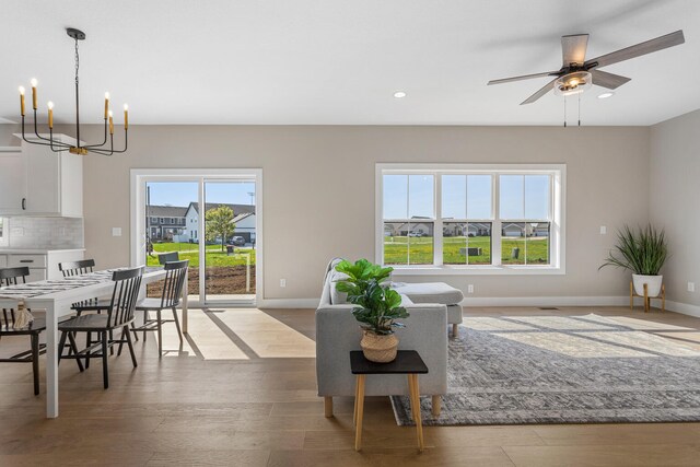 living area with recessed lighting, baseboards, wood finished floors, and ceiling fan with notable chandelier