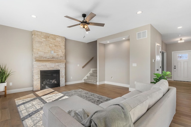 living area with a ceiling fan, visible vents, wood finished floors, and stairway