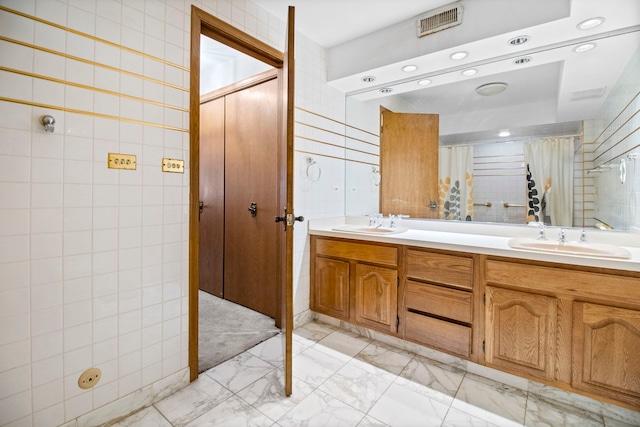 full bath with tile walls, marble finish floor, and a sink