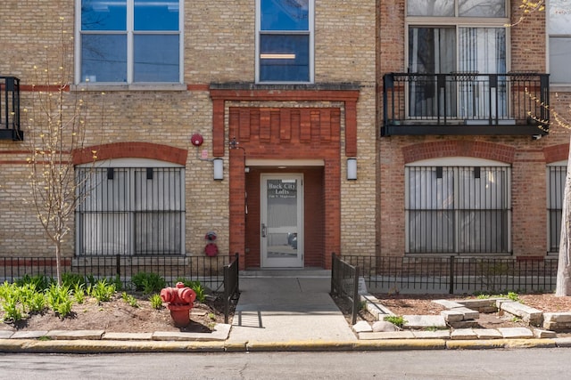 1740 N Maplewood Ave Unit 102, Chicago, IL 60647 - view of exterior entry featuring brick siding, fence, and a balcony