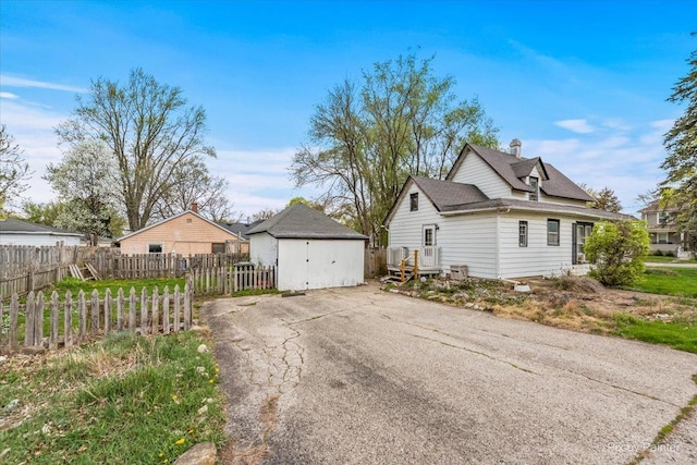 view of property exterior featuring an outdoor structure, roof with shingles, a storage unit, and fence