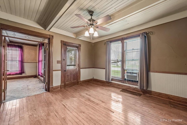 unfurnished room featuring light wood-style floors, a healthy amount of sunlight, and a wainscoted wall