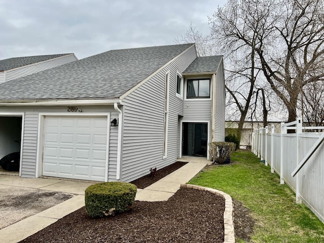 view of side of property featuring driveway, fence, a garage, a lawn, and a shingled roof