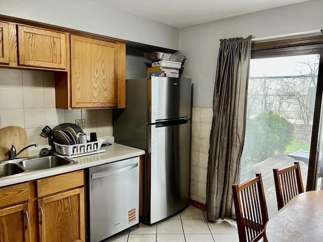 kitchen featuring light countertops, appliances with stainless steel finishes, brown cabinets, and a sink