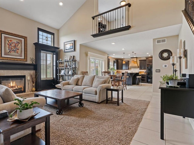living room with high vaulted ceiling, a glass covered fireplace, recessed lighting, light tile patterned floors, and visible vents