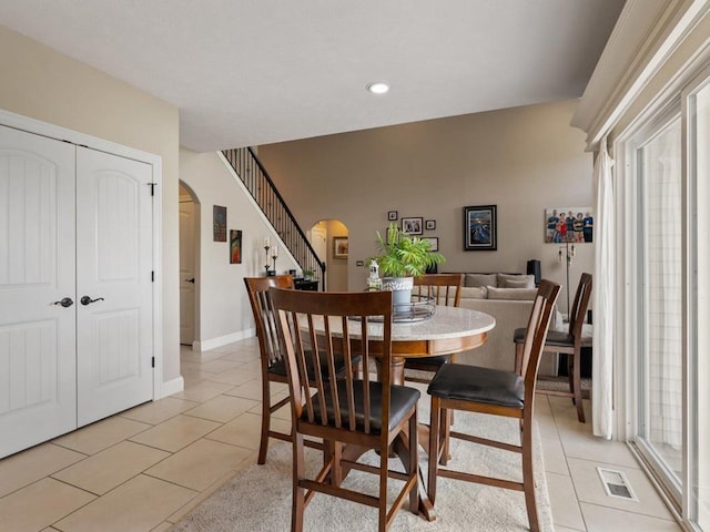 dining room with baseboards, arched walkways, light tile patterned flooring, and visible vents