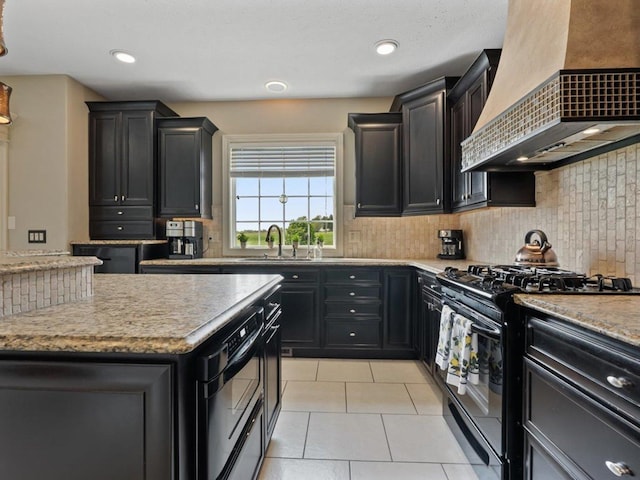 kitchen featuring dark cabinetry, a sink, premium range hood, and black gas stove