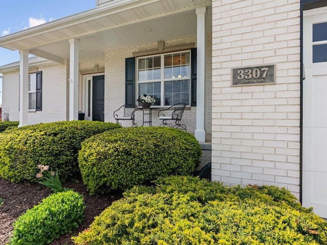 property entrance with covered porch and brick siding