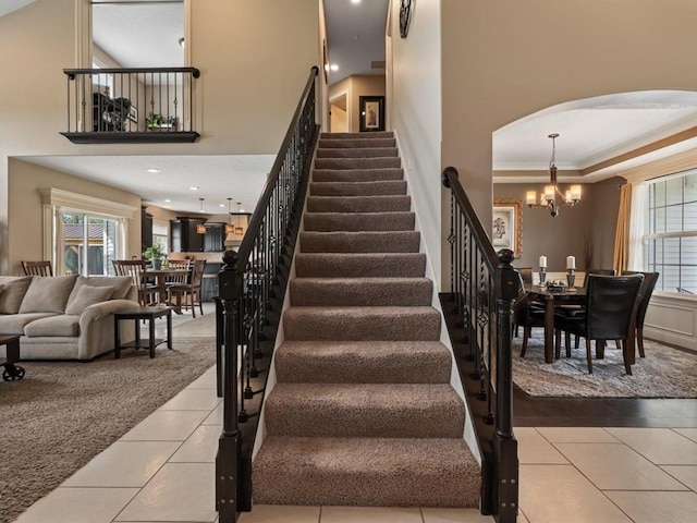 stairs with plenty of natural light, arched walkways, tile patterned flooring, and a notable chandelier