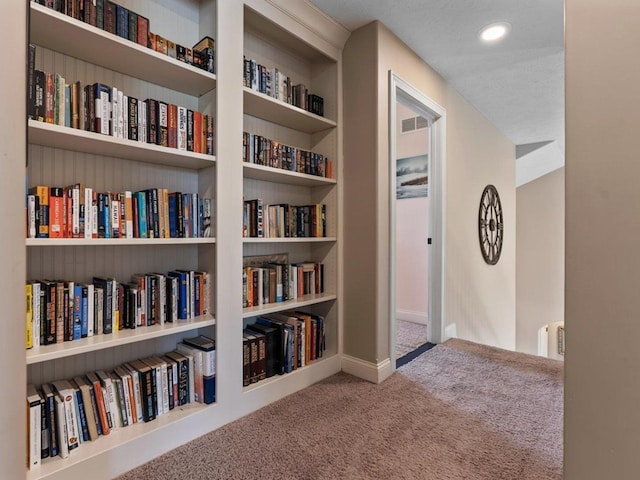 corridor featuring visible vents, built in features, carpet floors, baseboards, and recessed lighting