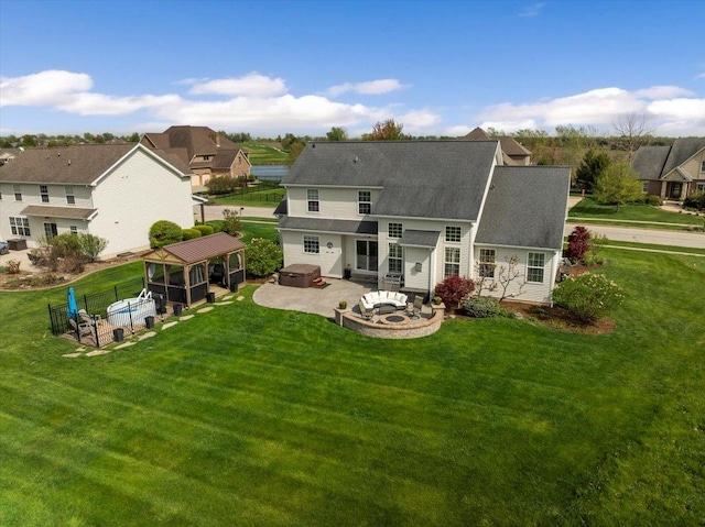 rear view of property featuring a lawn, a residential view, a patio area, fence, and a shingled roof