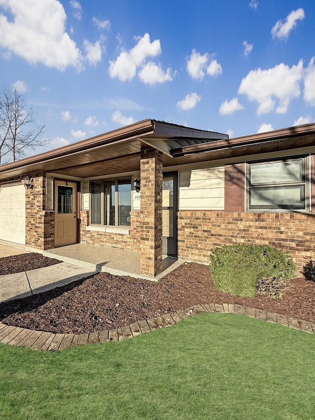 exterior space featuring solar panels, brick siding, a yard, and an attached garage