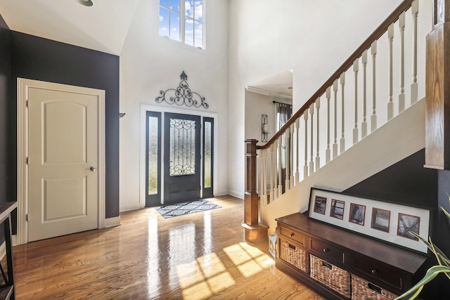 entryway featuring wood finished floors, a towering ceiling, and stairs
