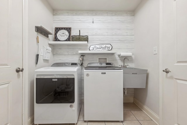clothes washing area featuring a sink, washing machine and dryer, baseboards, laundry area, and light tile patterned floors