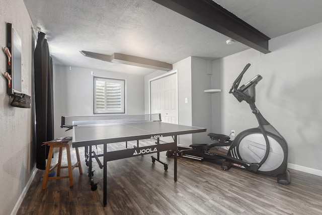 playroom with wood finished floors, a textured ceiling, baseboards, and beam ceiling