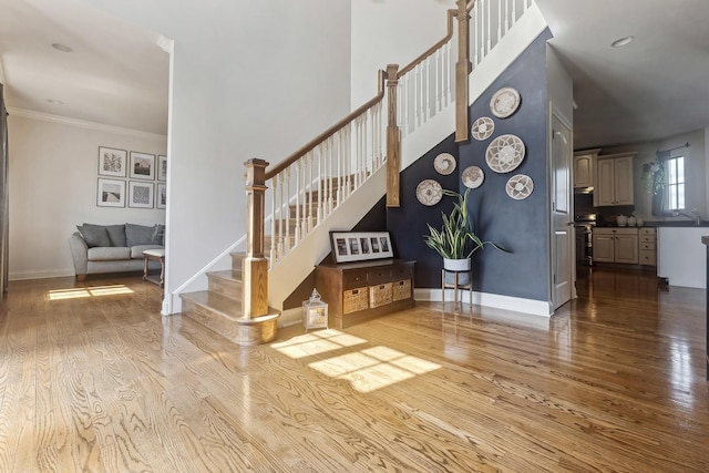 stairway with baseboards, wood finished floors, and crown molding