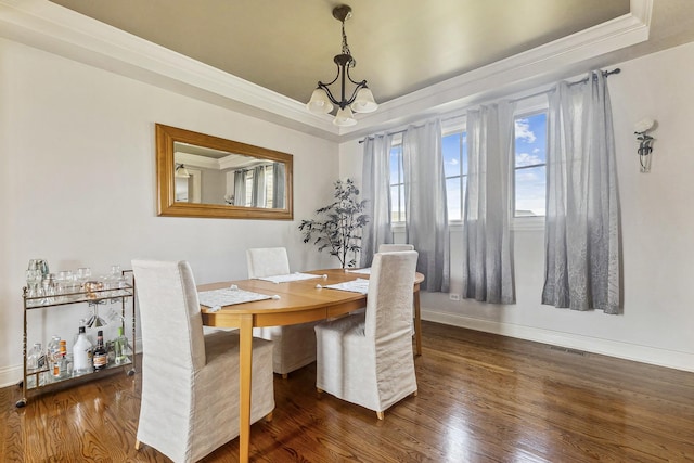 dining room featuring baseboards, wood finished floors, ornamental molding, and a tray ceiling