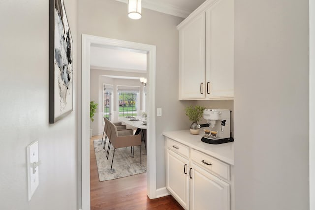 interior space featuring dark wood-style flooring, a chandelier, ornamental molding, and baseboards