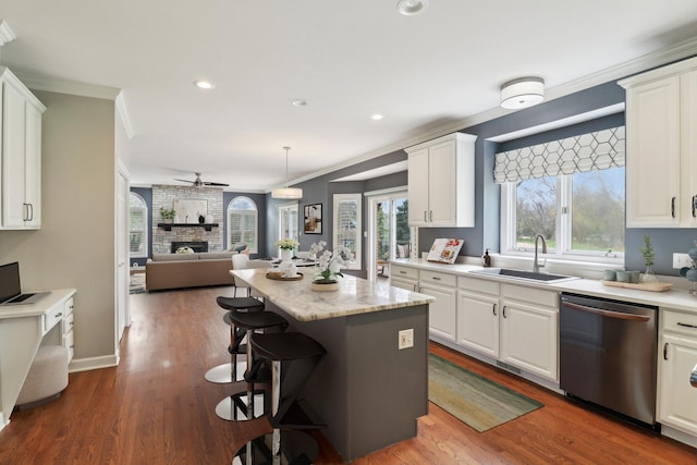 kitchen featuring a kitchen breakfast bar, stainless steel dishwasher, a sink, a center island, and open floor plan