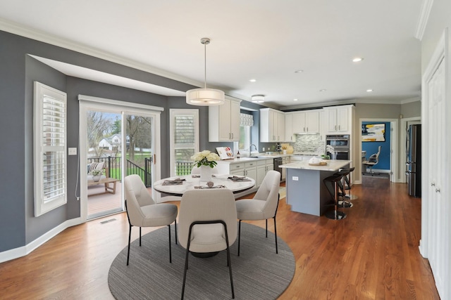 dining area with wood finished floors, recessed lighting, ornamental molding, and baseboards