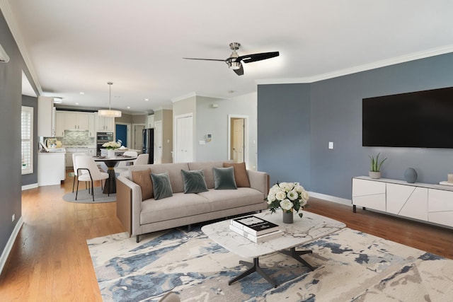 living area with recessed lighting, crown molding, a ceiling fan, baseboards, and wood finished floors
