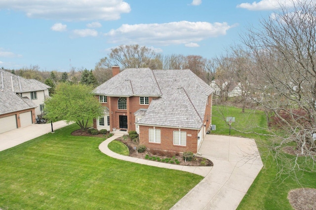 view of front of house featuring a chimney, brick siding, a garage, a front yard, and concrete driveway