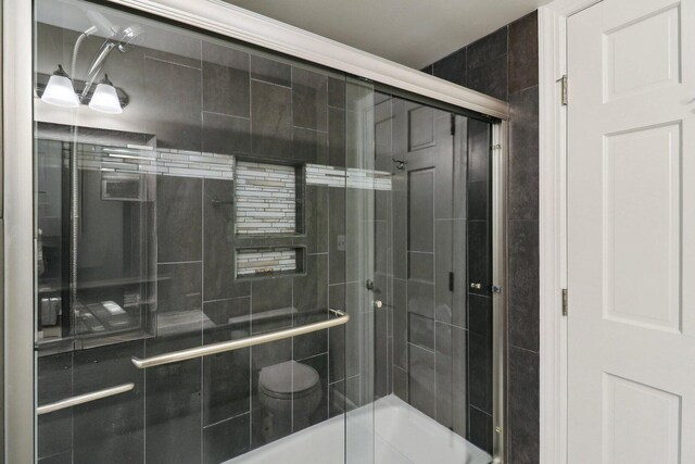 full bath with toilet and a tile shower