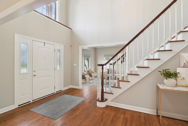 foyer featuring stairway, wood finished floors, and a high ceiling