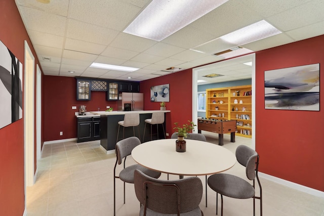 dining area with baseboards, indoor wet bar, and a paneled ceiling