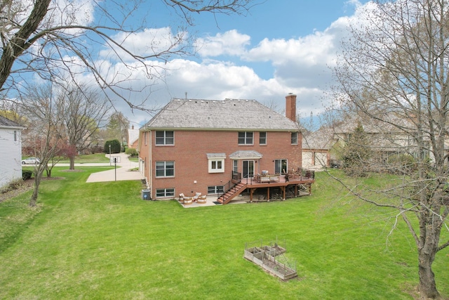 rear view of house featuring a chimney, brick siding, a wooden deck, and a lawn