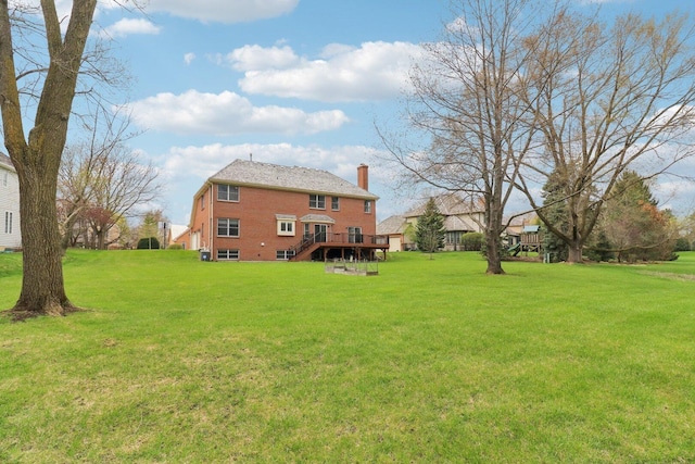 back of house with stairs, a chimney, a deck, a yard, and brick siding