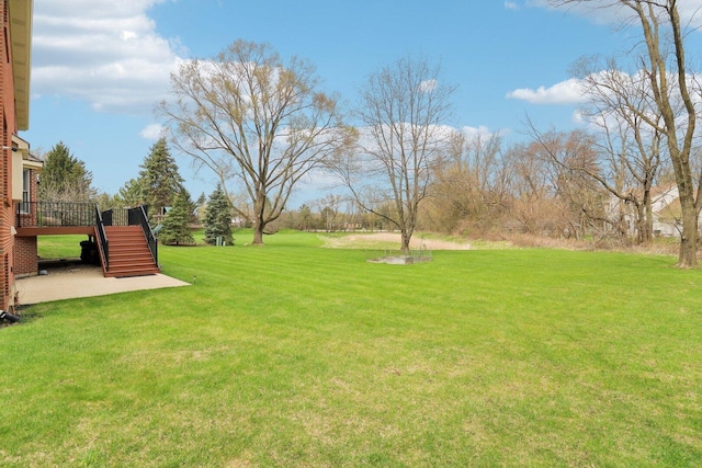 view of yard with a deck, a patio, and stairs