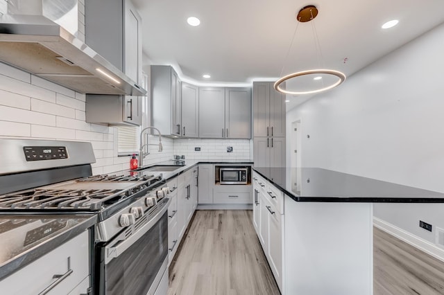 2147 N Latrobe Ave, Chicago, IL 60639 - kitchen with stainless steel appliances, wall chimney range hood, a sink, light wood-type flooring, and a kitchen island