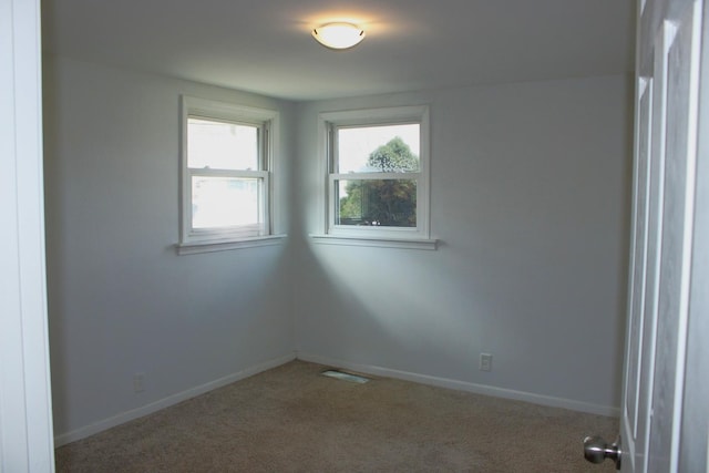 carpeted empty room featuring visible vents and baseboards
