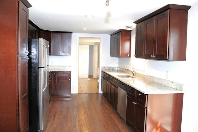 kitchen featuring recessed lighting, dark wood-style floors, light stone counters, stainless steel appliances, and a sink