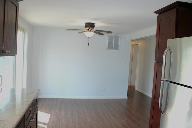 kitchen featuring a ceiling fan, dark wood finished floors, light stone countertops, visible vents, and freestanding refrigerator