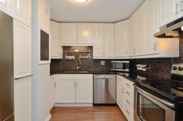 kitchen with a sink, under cabinet range hood, white cabinets, and stainless steel appliances