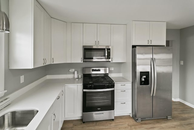 kitchen featuring appliances with stainless steel finishes, light wood-style flooring, light countertops, and white cabinets