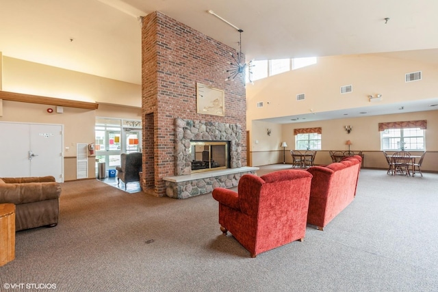living room featuring carpet floors, a towering ceiling, a stone fireplace, and visible vents