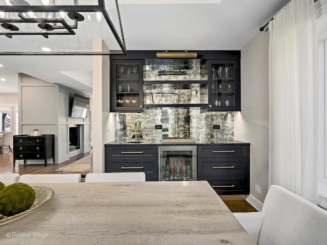 bar with wood finished floors, decorative backsplash, beverage cooler, indoor wet bar, and an inviting chandelier