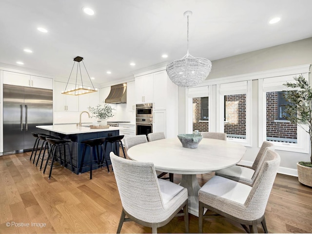 dining space with an inviting chandelier, light wood-style floors, and recessed lighting