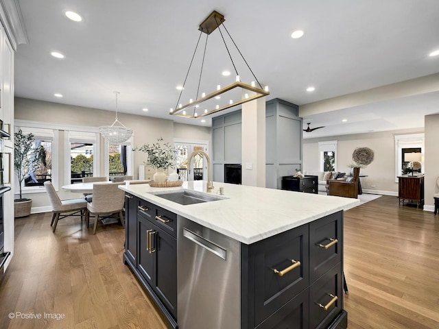 kitchen featuring recessed lighting, wood finished floors, stainless steel dishwasher, a sink, and open floor plan