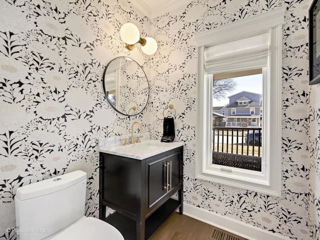 bathroom featuring wallpapered walls, wood finished floors, toilet, and crown molding