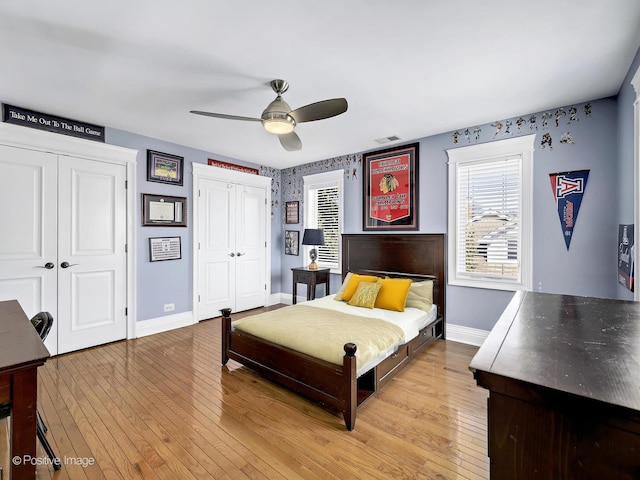 bedroom featuring light wood-style floors, multiple closets, baseboards, and multiple windows