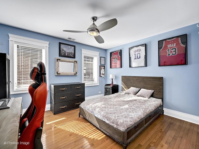 bedroom featuring hardwood / wood-style flooring, visible vents, baseboards, and multiple windows